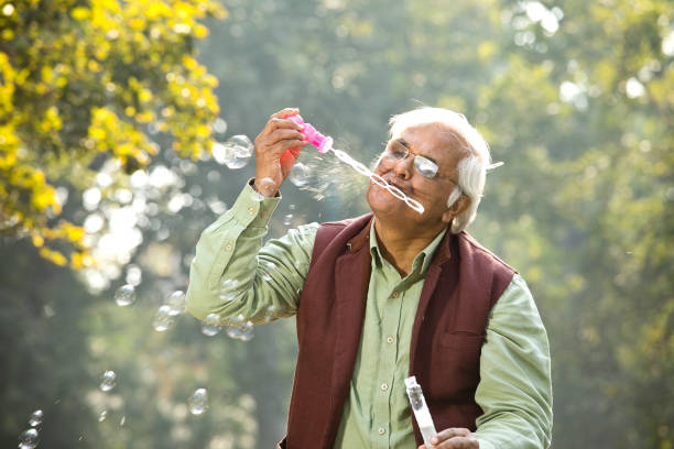 istock Senior men enjoying blowing bubbles at park 1295226139