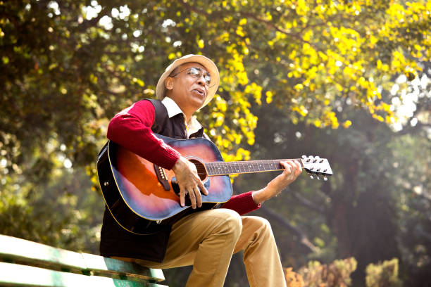istock Senior man playing guitar at park 1295226383