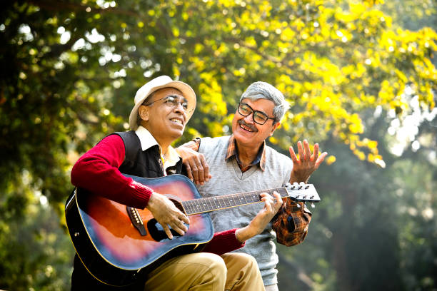 istock Two senior men playing guitar and having fun at park 1295226501