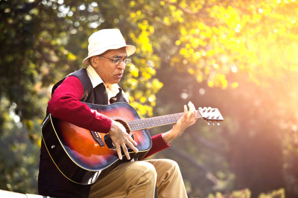 istock Senior man playing guitar at park 1295226626