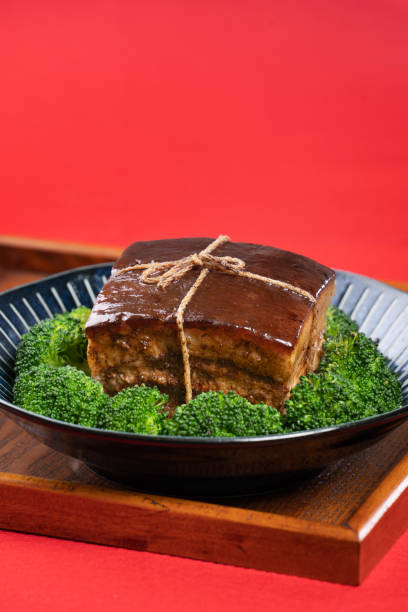 Dong Po Pork meat in a blue plate with broccoli with red background.