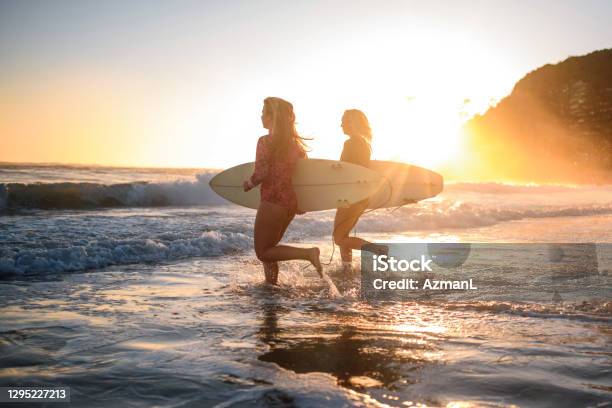 Young Female Surfers Running Into Water At Burleigh Heads Stock Photo - Download Image Now