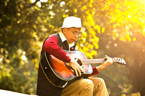 istock Senior man playing guitar at park 1295230419