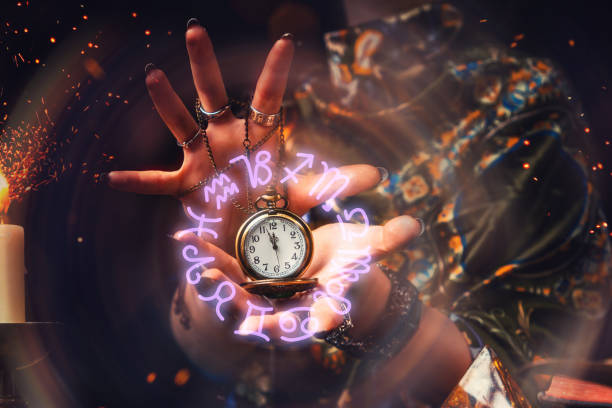 The fortune teller holds a watch on a chain in her hands and conjures over it. A luminous zodiac circle is depicted around the clock. The concept of divination, astrology and predicting the future