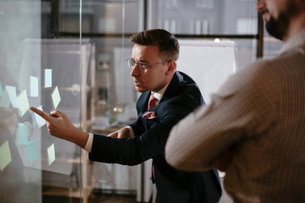 istock Business people in conference room use sticky notes on glass wall. 1295239382