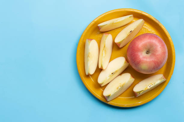 istock Ripe apples on yellow plate on blue background. 1295241333