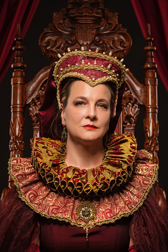 Beautiful historical Queen character wearing a period dress in a studio shot