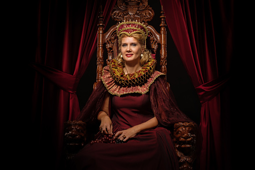 Beautiful historical Queen character wearing a period dress in a studio shot