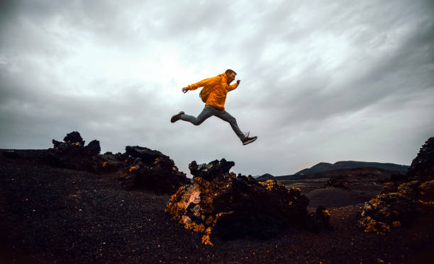 Hiker man jumping over the mountain. Freedom, risk, success and challenge. Focus on man