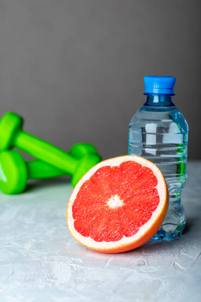 istock Dumbbells, half grapefruit and bottle of water on the table. 1295250259