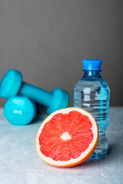 istock Dumbbells, half grapefruit and bottle of water on the table. 1295250260