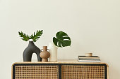 モダンなスカンジナビアの家のインテリアは、デザインの木製のコモード、花瓶のトロピカルリーフ、本、スタイリッシュな家の装飾の個人的なアクセサリーを備えています。テンプレート�