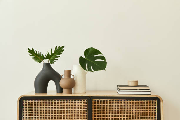 디자인 나무 commode, 꽃병열대 잎, 세련된 홈 장식의 책과 개인 액세서리와 현대적인 스칸디나비아 홈 인테리어. 템플릿. 공간을 복사합니다. 흰색 벽. - 모델하우스 내부 뉴스 사진 이미지