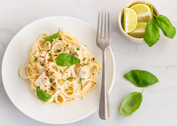 makaron linguine w białym sosie ozdobiony liśćmi bazylii bezpośrednio nad zdjęciem - italian cuisine linguini chicken pasta zdjęcia i obrazy z banku zdjęć