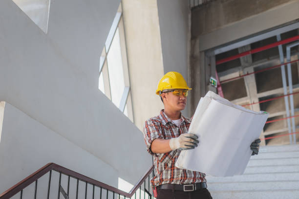istock Asian Construction engineer in hardhat looking at blueprints at construction site, Engineers at work checking construction building project on site 1295265054