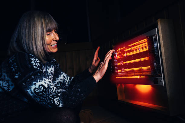 Infrared rays are the best Mature woman warming her hands with the satisfying infrared rays of an electric bar fire. electric heater photos stock pictures, royalty-free photos & images