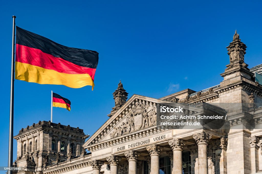 The federal flag in front of the impressive Reichstag in Berlin as a symbol of democracy The german Reichstag with a dedication to the people in the German capital Berlin Bundestag Stock Photo