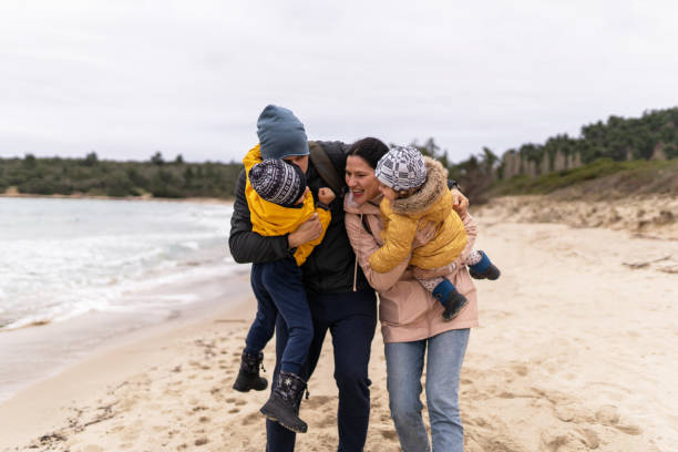 istock Young couple spending time with their two kids on beach on cold day 1295277208