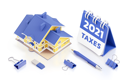 The 3D-model of a private two-storey house beside to a desk calendar for the 2021 year together with stationery accessories, which are arranged on reflective white surface. 3D rendering graphics on the theme of Tax Payments.