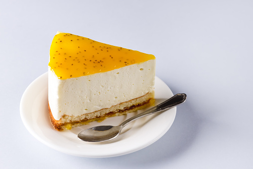 Slice of Cheesecake or Yogurt Cake with Passion Fruit Jam Tasty Homemade Dessert Blue Background Horizontal