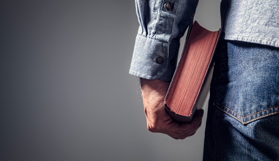 Hombre sosteniendo la Biblia sagrada con fondo gris para el texto photo