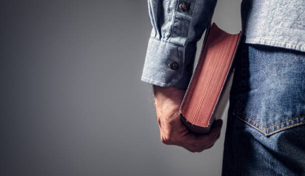 uomo che tiene la sacra bibbia con sfondo grigio per il testo - bible study foto e immagini stock