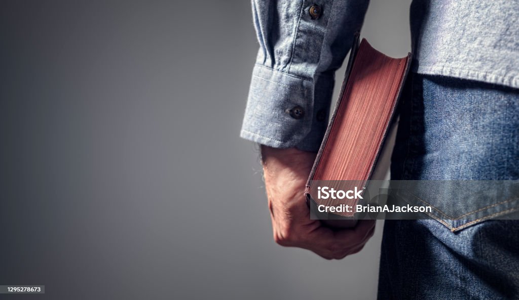 Man holding holy bible with gray background for text Man holding holy bible over gray background for copy concept for religion, praying, education and bible study Bible Stock Photo