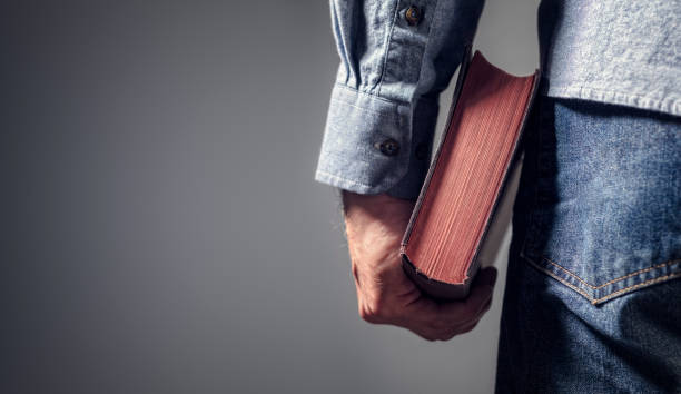 homem segurando bíblia sagrada com fundo cinza para texto - holy book - fotografias e filmes do acervo