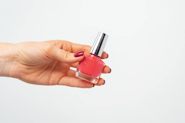 istock Female hand holding nail polish against white background 1295278903