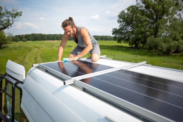 istock Man wiping clean a solar panel on top of a van 1295282024