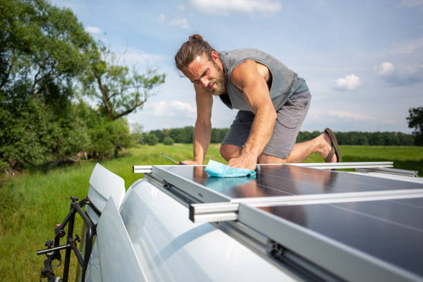 istock Man cleaning a solar panel on top of a caravan 1295282084