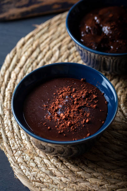 istock Dark chocolate mousse in a ceramic bowl on wooden table. Dark chocolate pudding with cocoa powder on top. 1295286455