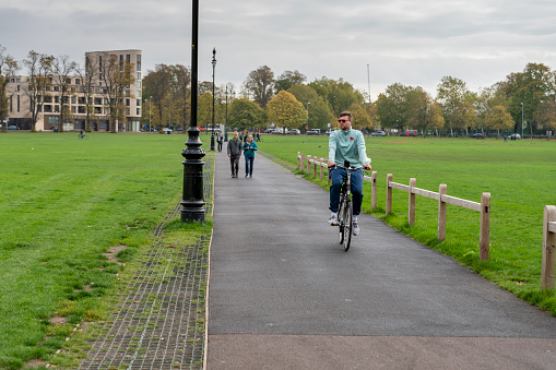 Footpath and cycleway through Parker's Piece, Cambridge, UK.  There is a student cycling towards the camera.