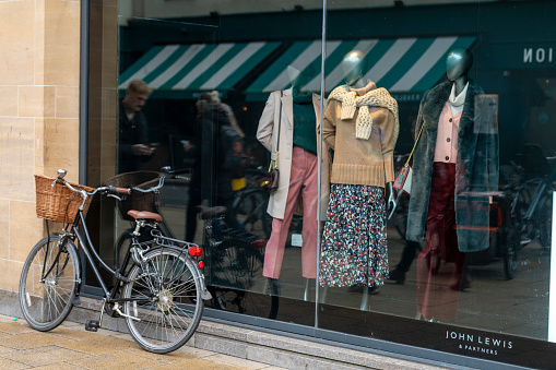Exterior of John Lewis shop in Cambridge, a city in England famous for its prestigious university, established in the 12th century. There is a shopper bike leant up against the store window.