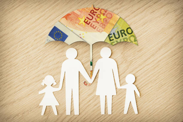 Paper family silhouette with umbrella made of euro banknotes on wooden background - Concept of family financial protection stock photo