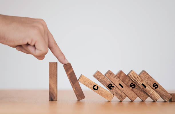 istock Stop crisis and risk management concept , Man using finger to stop wooden domino which falling to one wooden block still standing. 1295292931