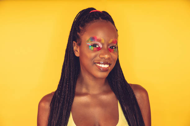 istock Woman posing with a rainbow colored makeup on a yellow background 1295294394