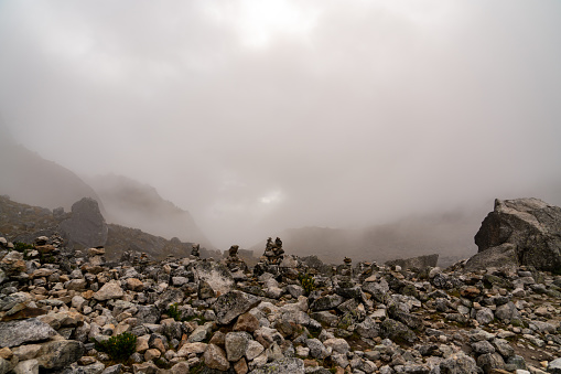 Traveller cairns on top of the tallest Peruvian mountain in fog, peaceful and idyllic.