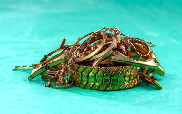 A scrap of gold. Old and broken jewelry watches of gold and gold-plated on a colored background.
