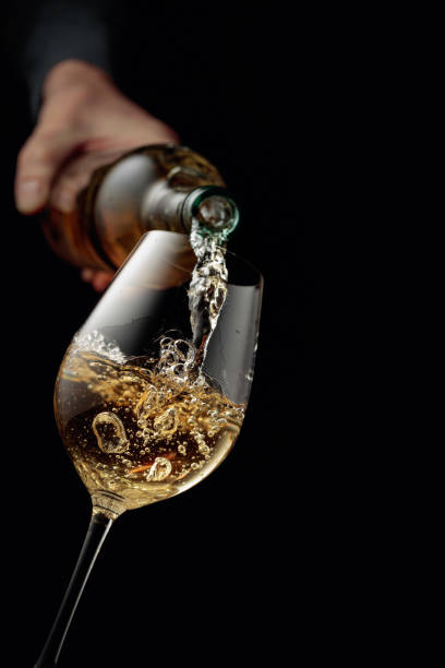 istock Pouring white wine in a glass goblet. 1295298040