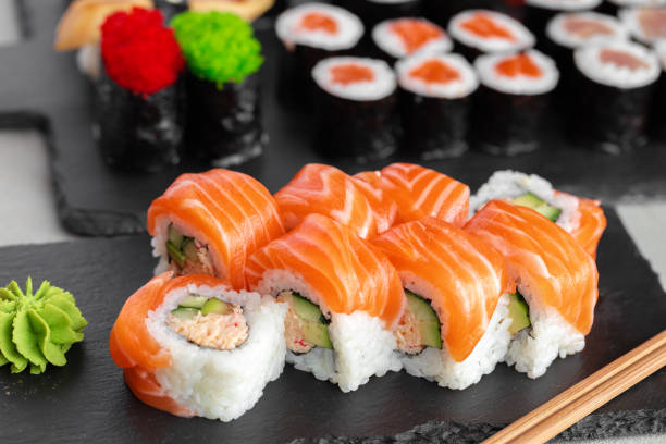 istock Sushi roll covered with fresh salmon served on plate 1295299932