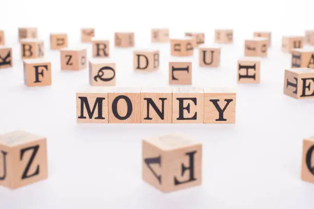 Photo of Money concept. Close up view photo of wooden cubes making showing word money isolated white desk backdrop