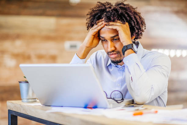 istock Tired young man in modern office working on laptop 1295301788