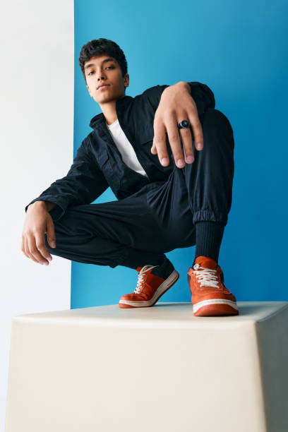 istock Confident young trendy mixed race man posing in studio sitting on big cube 1295303968