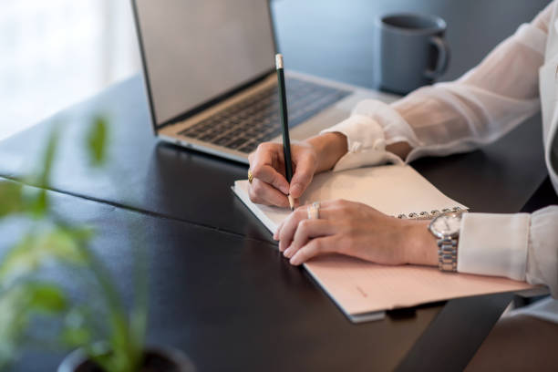 istock Close up. Businesswoman writing on a blank notebook on the table at office. 1295309773