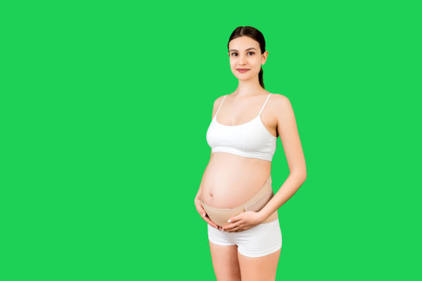 ritratto di benda di supporto su donna incinta in biancheria intima su sfondo verde con spazio di copia. concetto di cintura di supporto addominale ortopedico - busto ortopedico foto e immagini stock