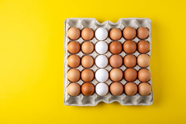 istock Nice big rural fresh eggs in cardboard egg box holder with colorful yellow background. 1295311926