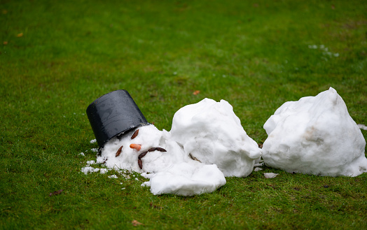 Un hombre de nieve derretido con una cara triste como símbolo del final del invierno. photo