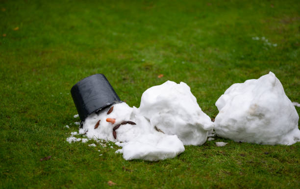 un hombre de nieve derretido con una cara triste como símbolo del final del invierno. - fundiendo fotografías e imágenes de stock