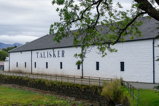 Carbost, Isle of Skye, Scotland - September 16 2020: The Talisker scotch malt whisky distillery seen from the shore of Loch Harport, which is in front of the distillery